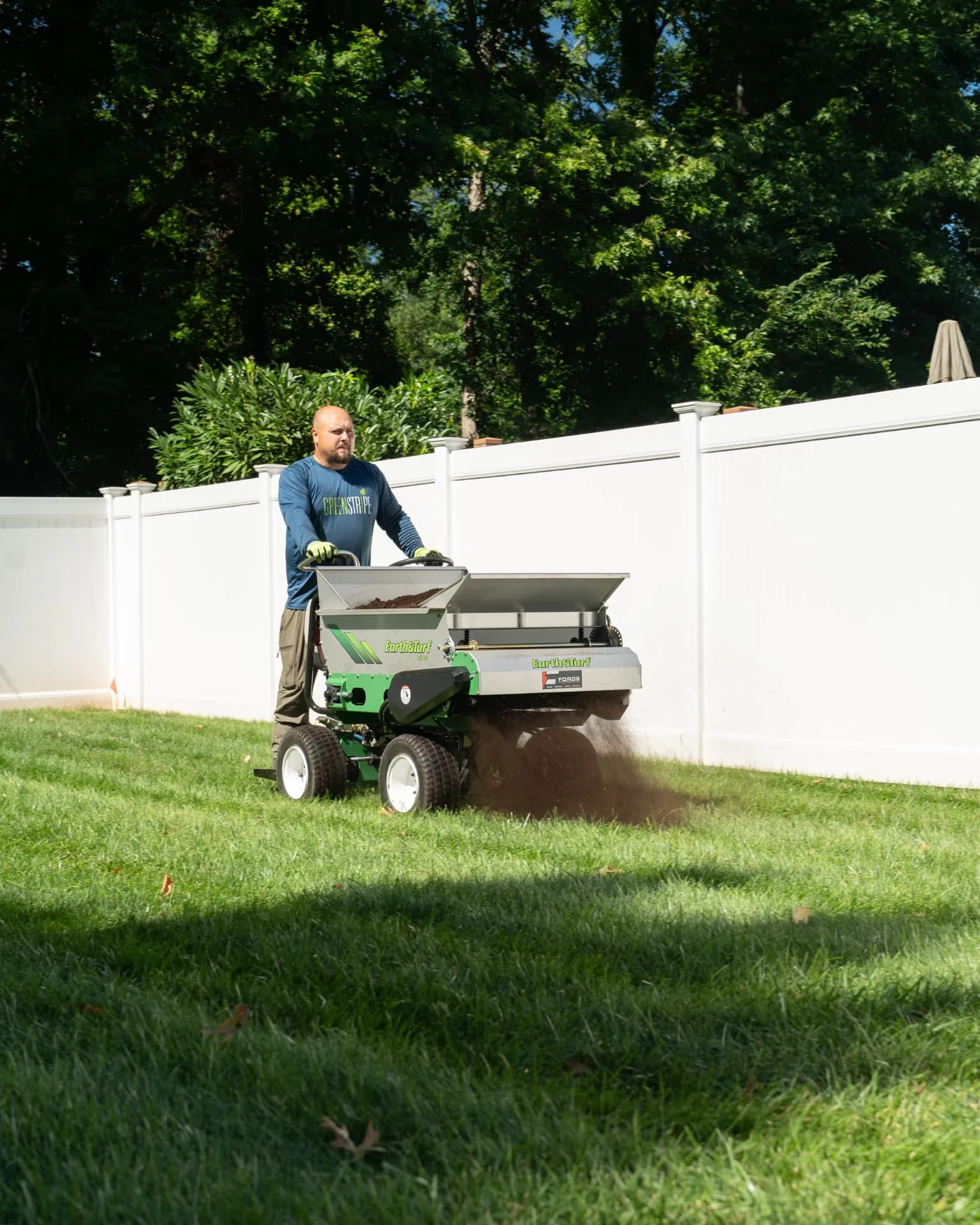 GreenStripe technician topdressing a backyard lawn with an Earth & Turf spreader